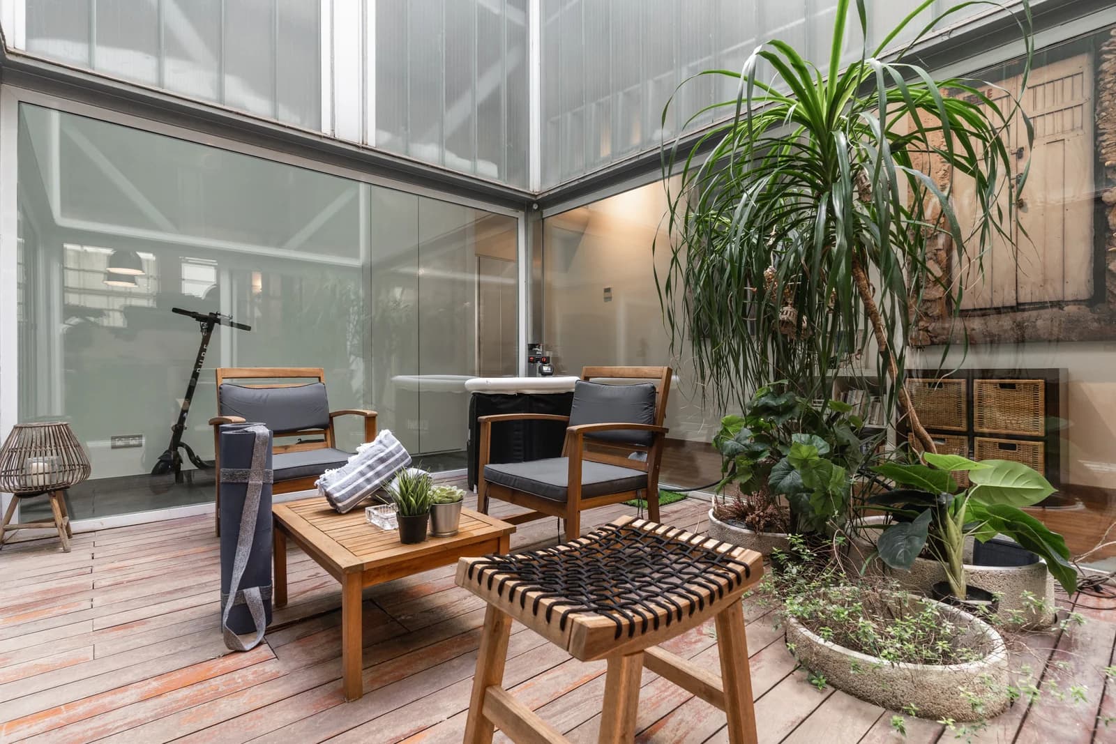 Glass-roofed indoor courtyard with timber decking and lush plants