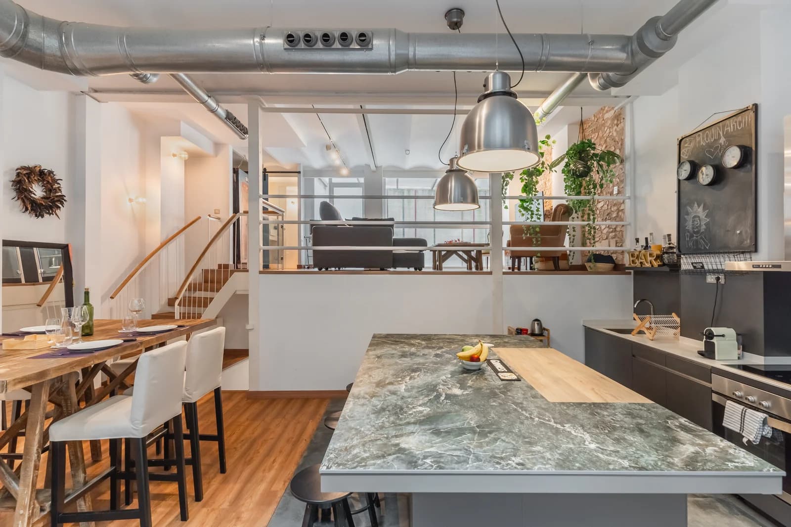Industrial kitchen with marble island and exposed ducting