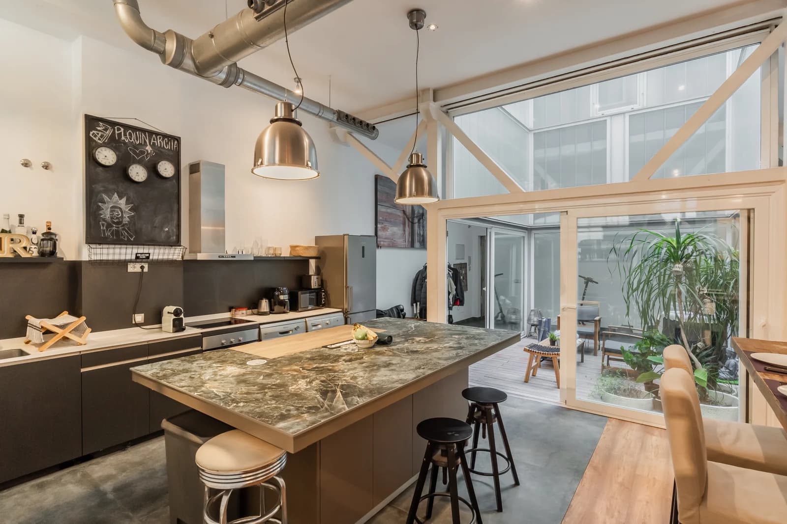 Marble island opens onto plant-filled glass atrium