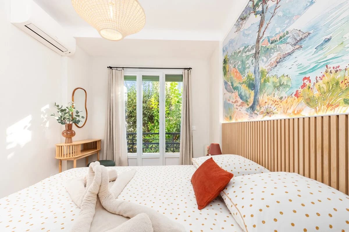 Sun-filled bedroom with painterly seascape mural and rust accents