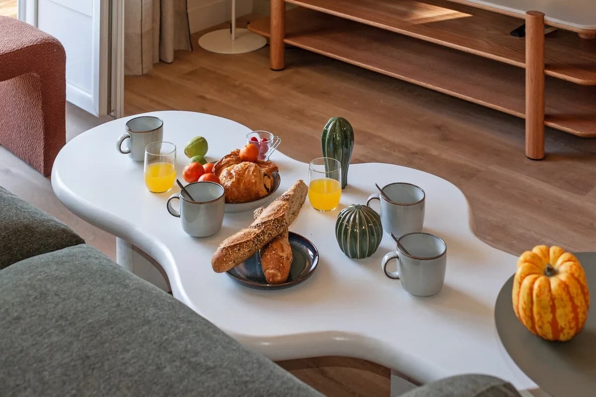 Cloud-shaped coffee table styled with pastries, juice, and ceramics