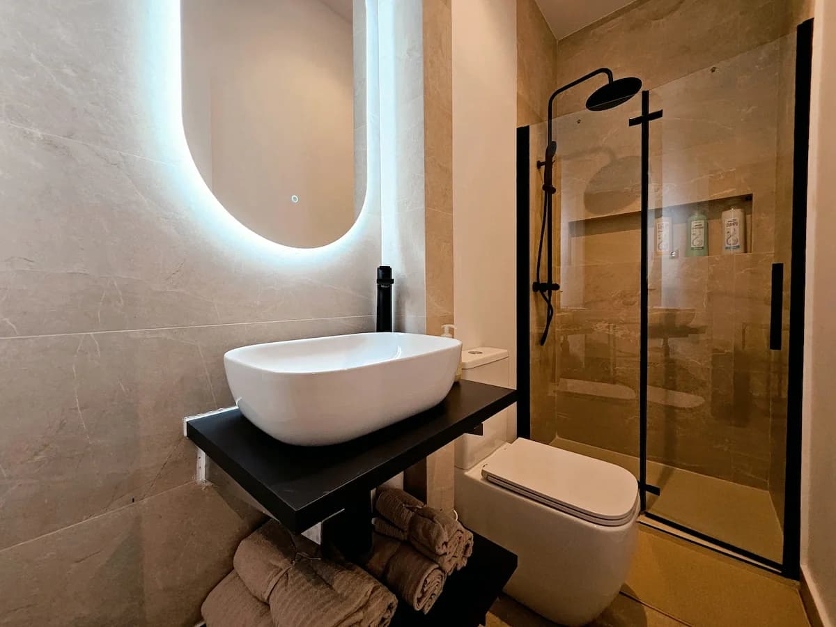 Moody bathroom with backlit mirror, vessel sink, and walk-in shower