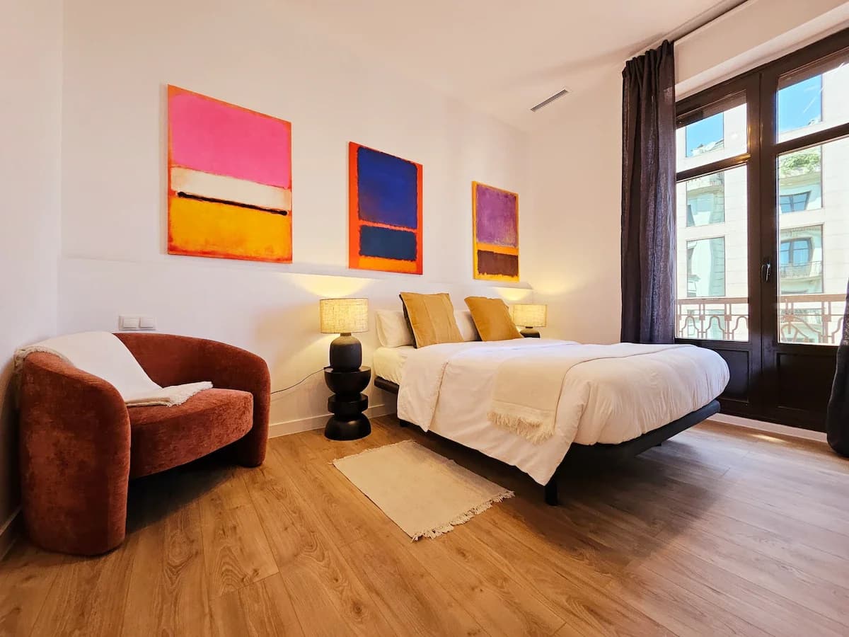 Bedroom with bold abstract triptych and burgundy reading chair