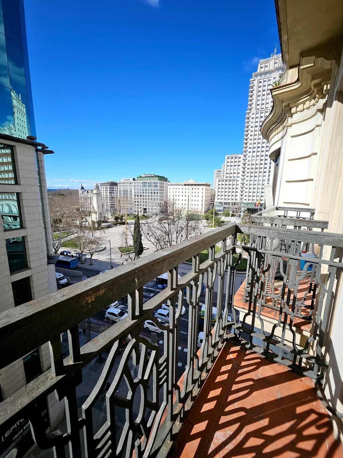Wrought-iron balcony perched above Madrid plaza with Torre de España