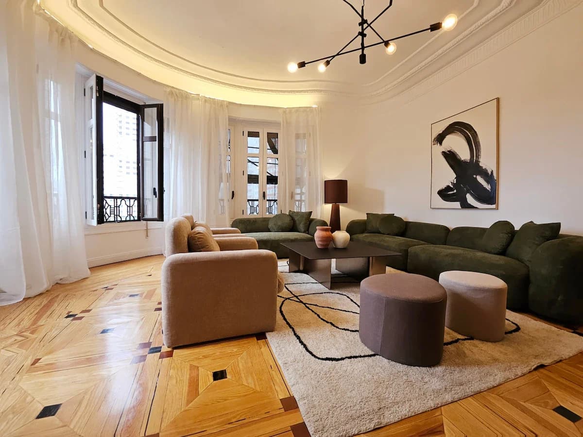Lounge corner with bouclé chairs and curved sofa under elegant moulding