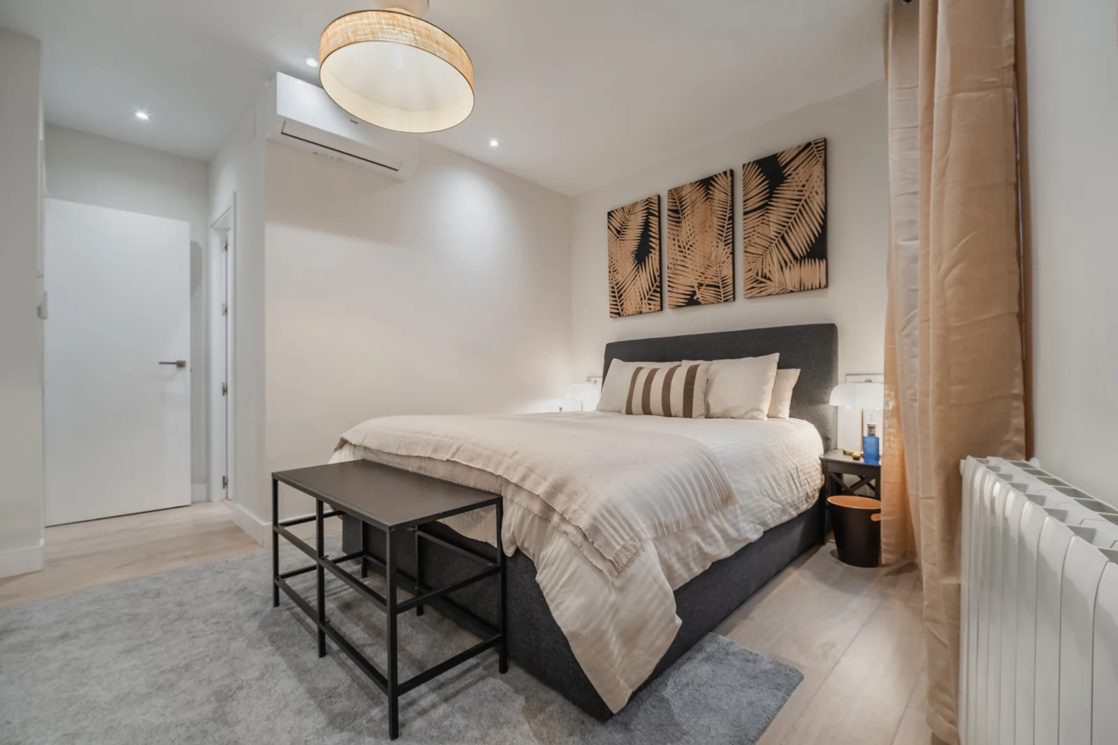 Bedroom with tropical leaf prints and pendant softening warm tones