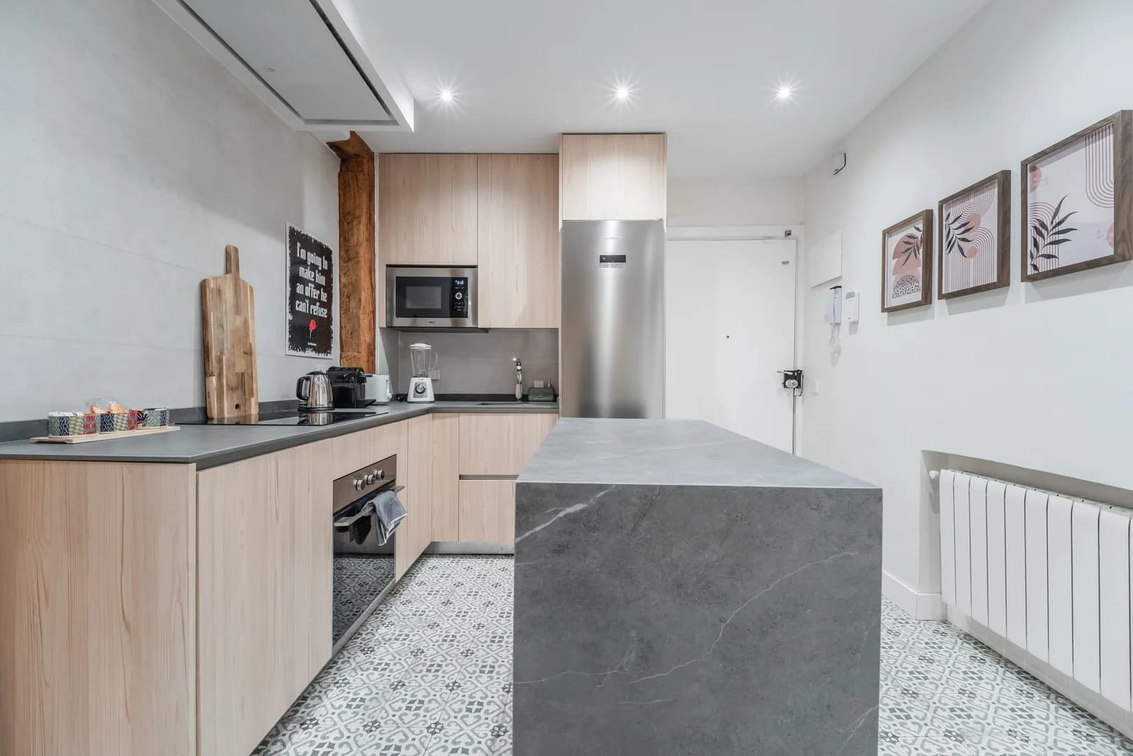Sleek kitchen with stone-clad island and patterned cement tile floor