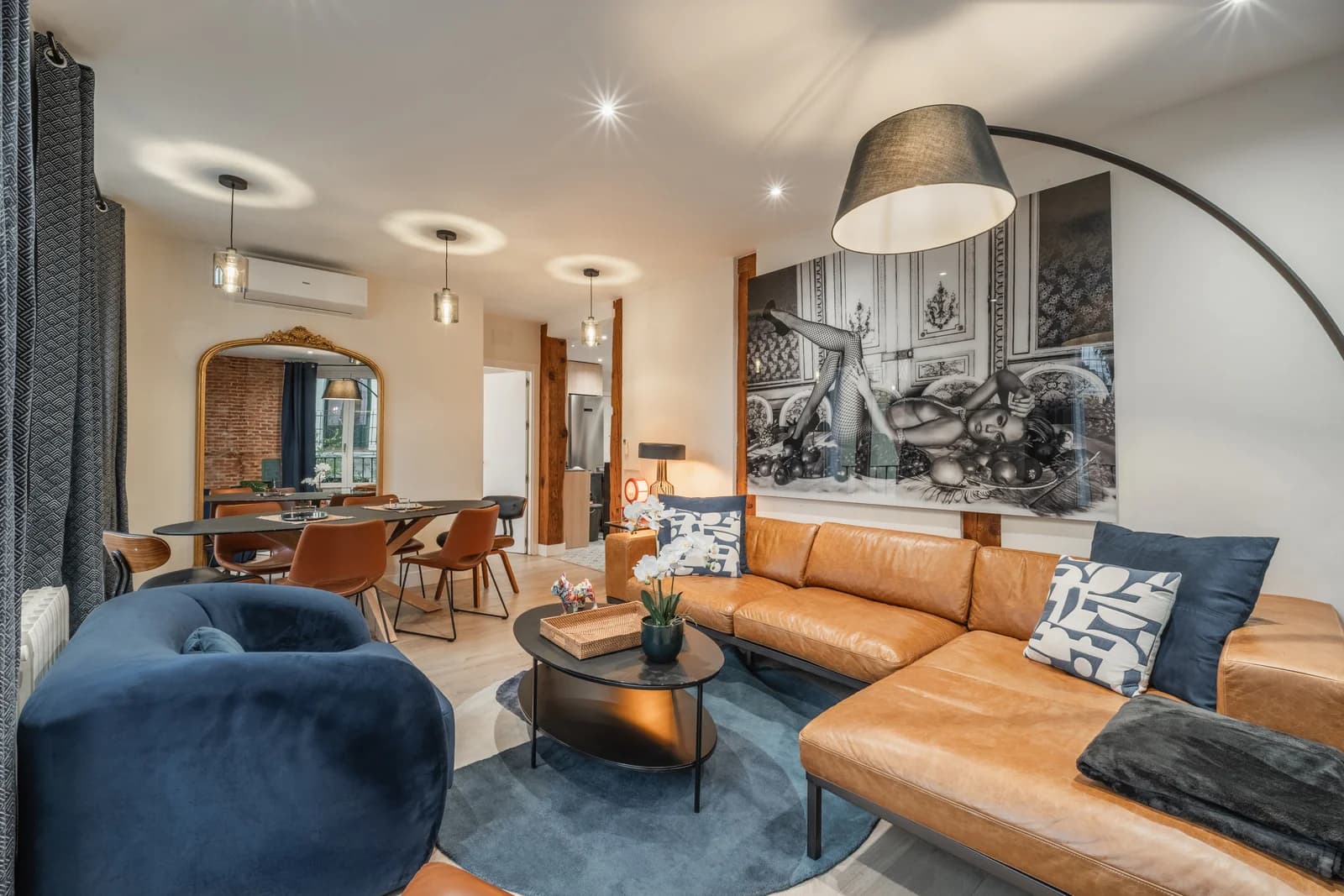 Lounge with arched mirror, tan sectional, and pendant cluster