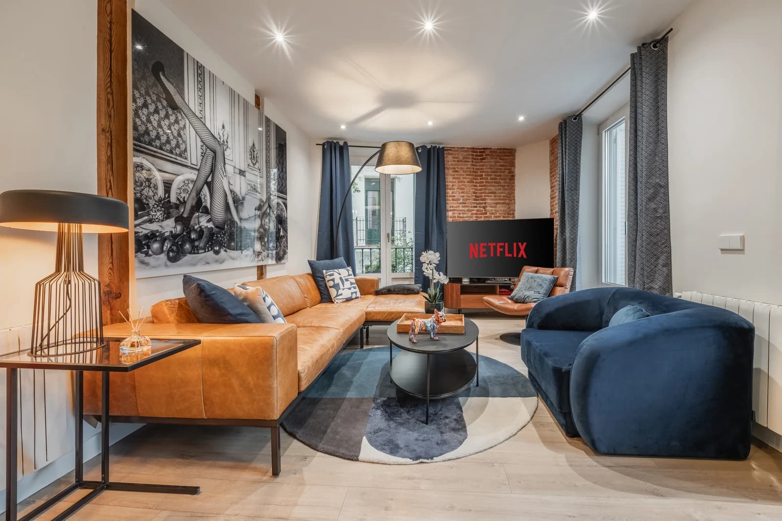 Sectional and velvet sofa anchoring living room with brick accent