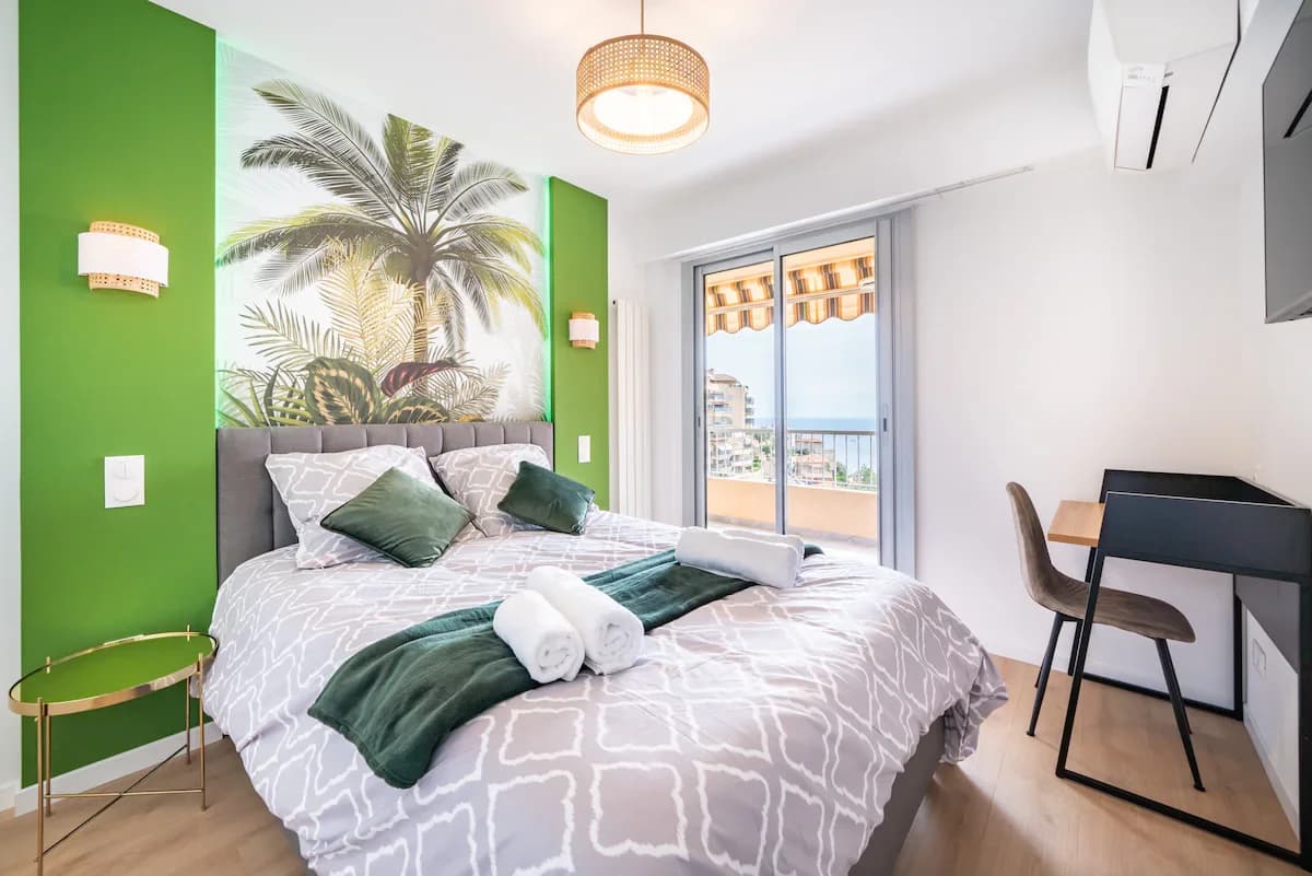 Bedroom with botanical palm mural and balcony framing sea view
