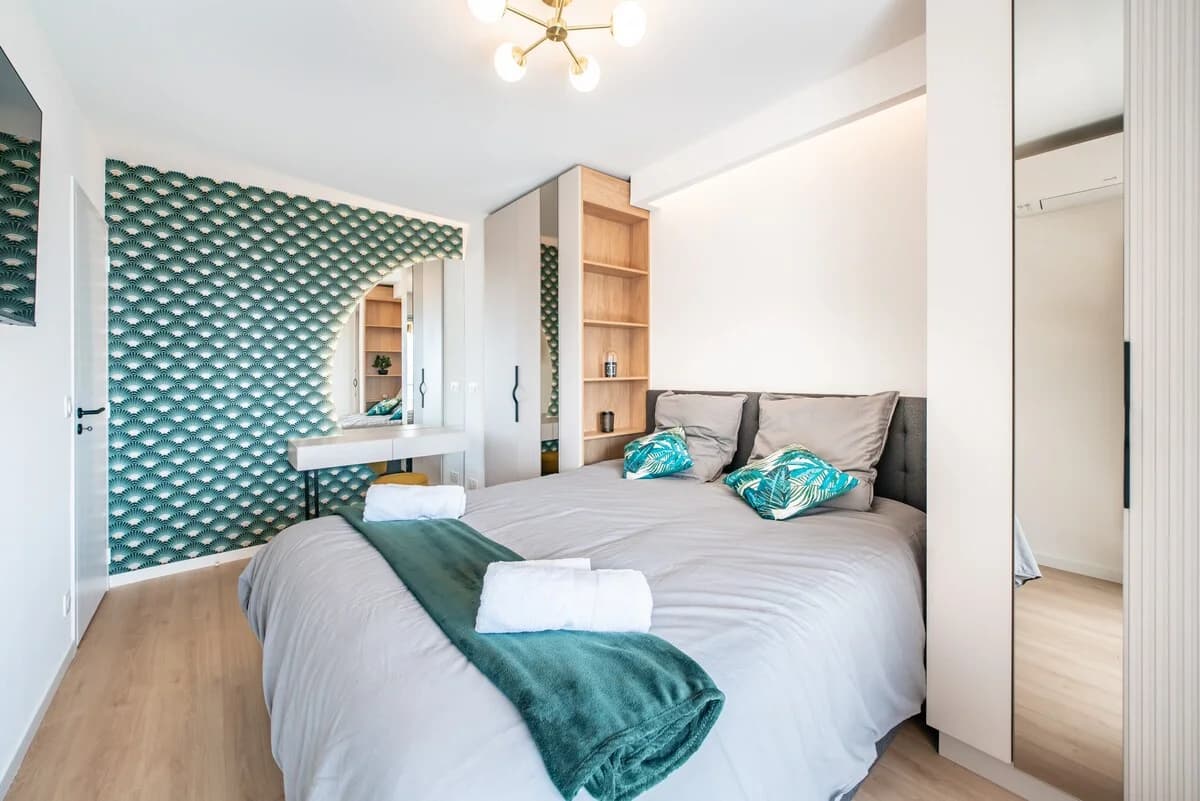 Bedroom with green art-deco wallpaper and twin beds against vanity