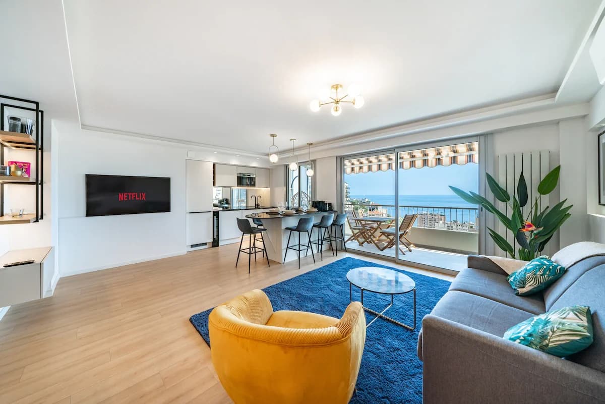 Compact living and dining with yellow accent chair and sea-view balcony