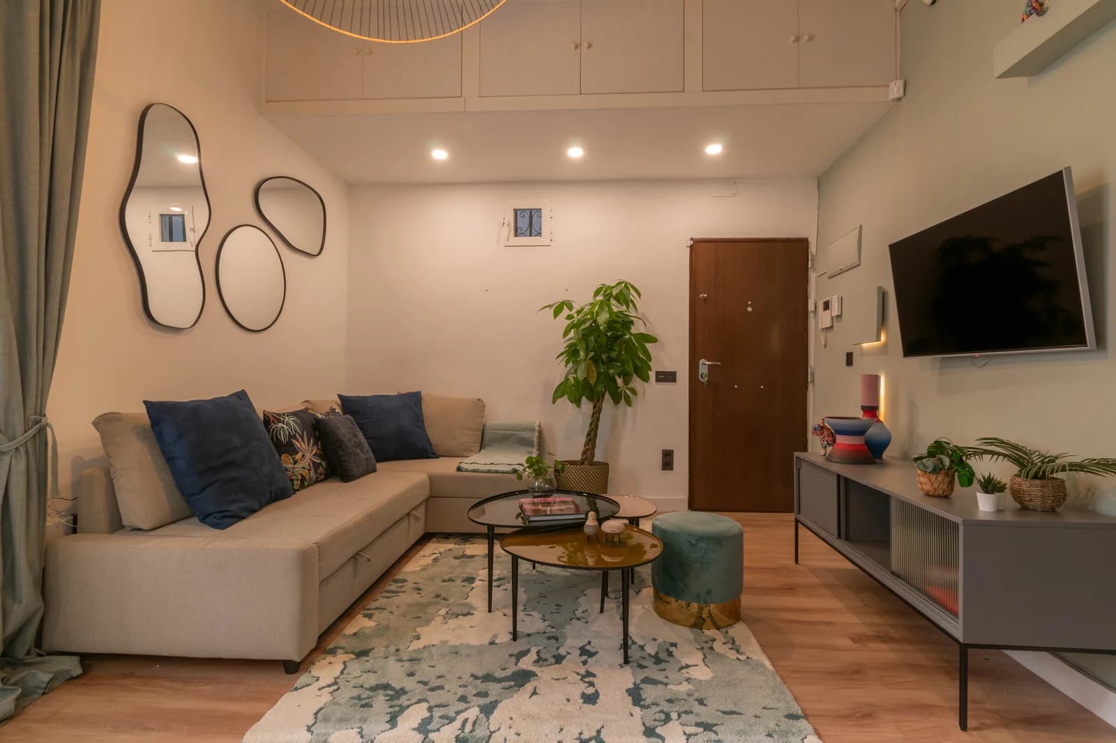 Living room with double-height ceiling, mirror cluster, and warm sofa