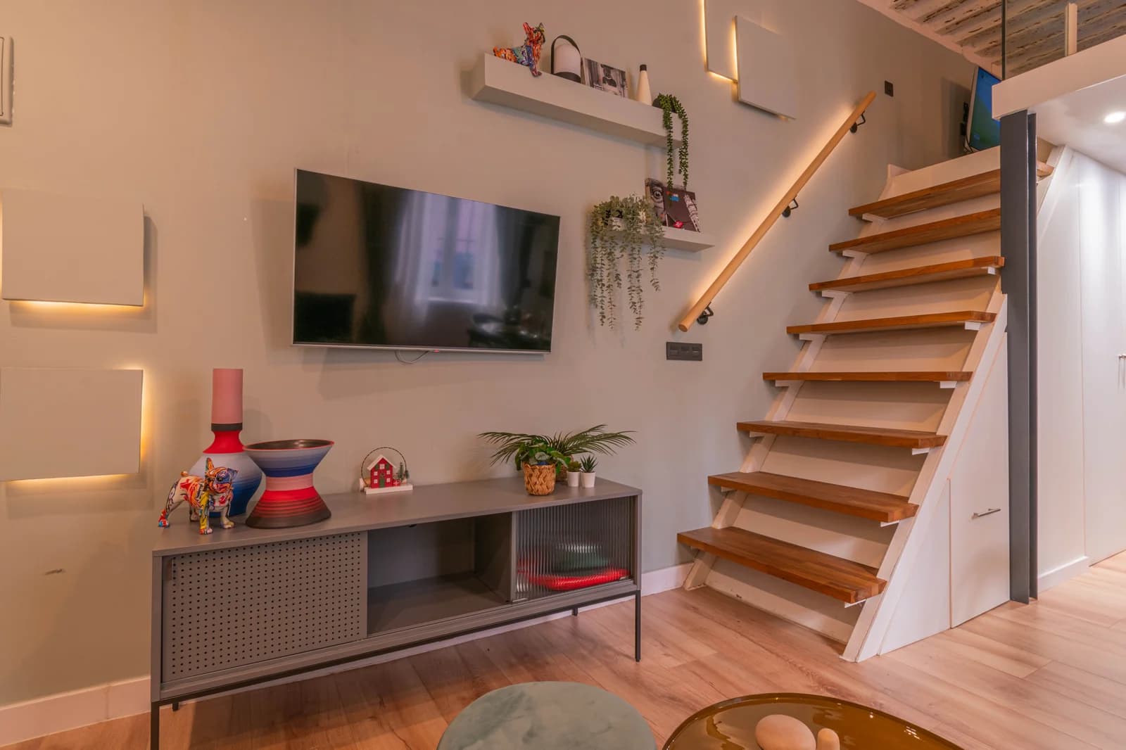 Open-tread staircase rising past console anchoring lower lounge
