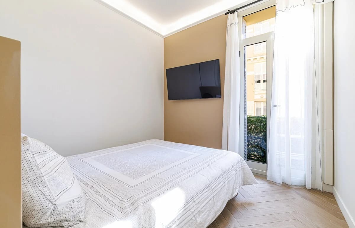 Bright bedroom with French doors opening to wrought-iron balcony