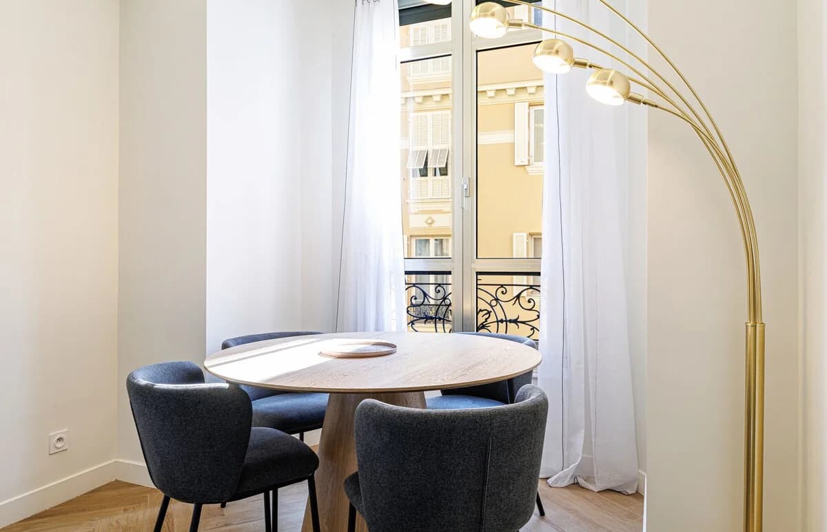 Round dining table by French balcony with brass arc floor lamp