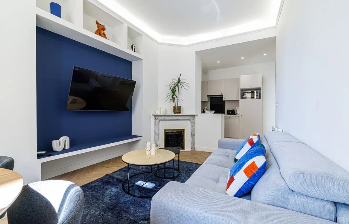 Living room with marble fireplace, blue accent wall, and herringbone floor