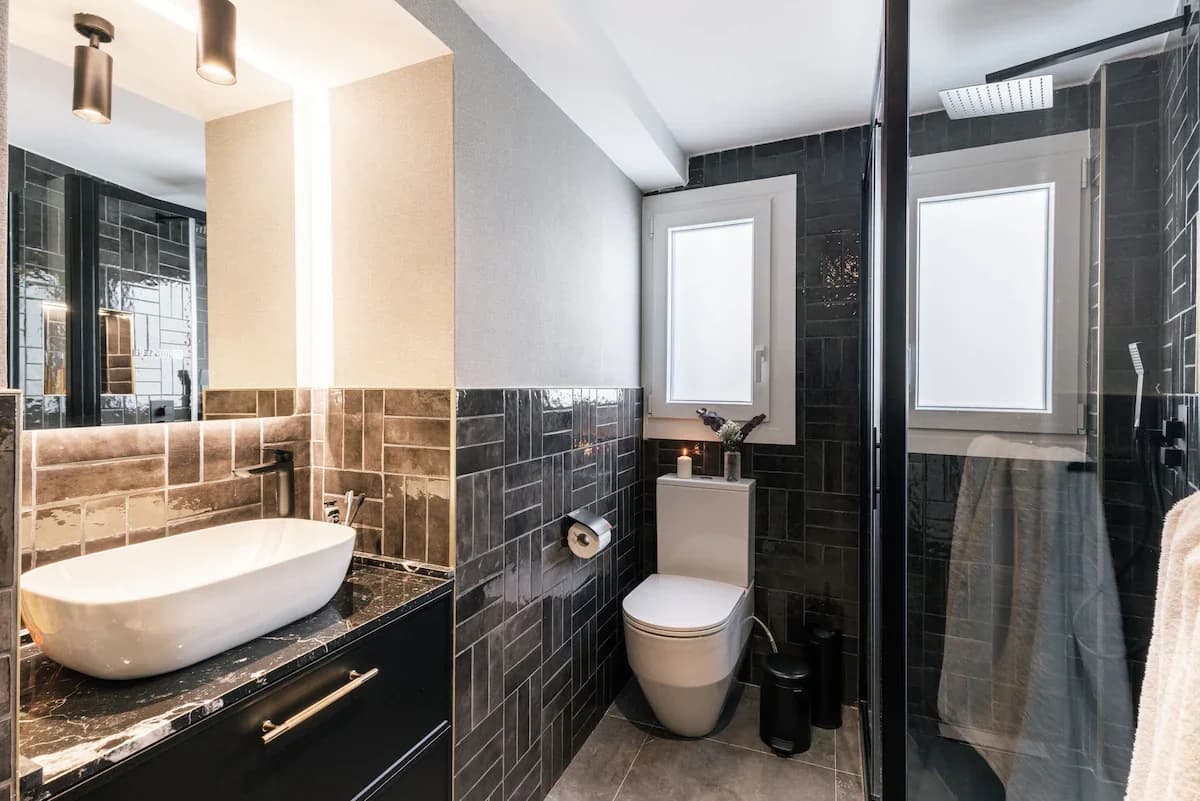Bathroom with black metro tile and amber-glow backlit mirror