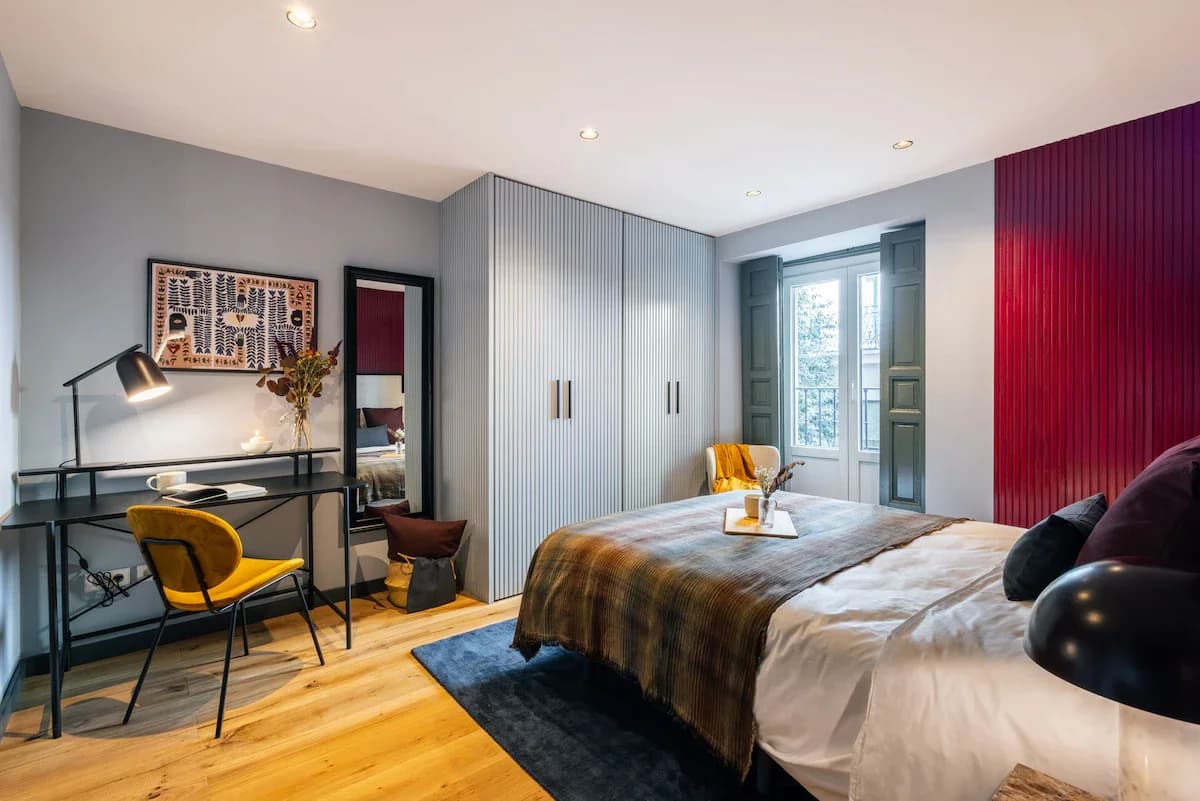 Bold bedroom with crimson reeded wall, blue shutters, and yellow accent