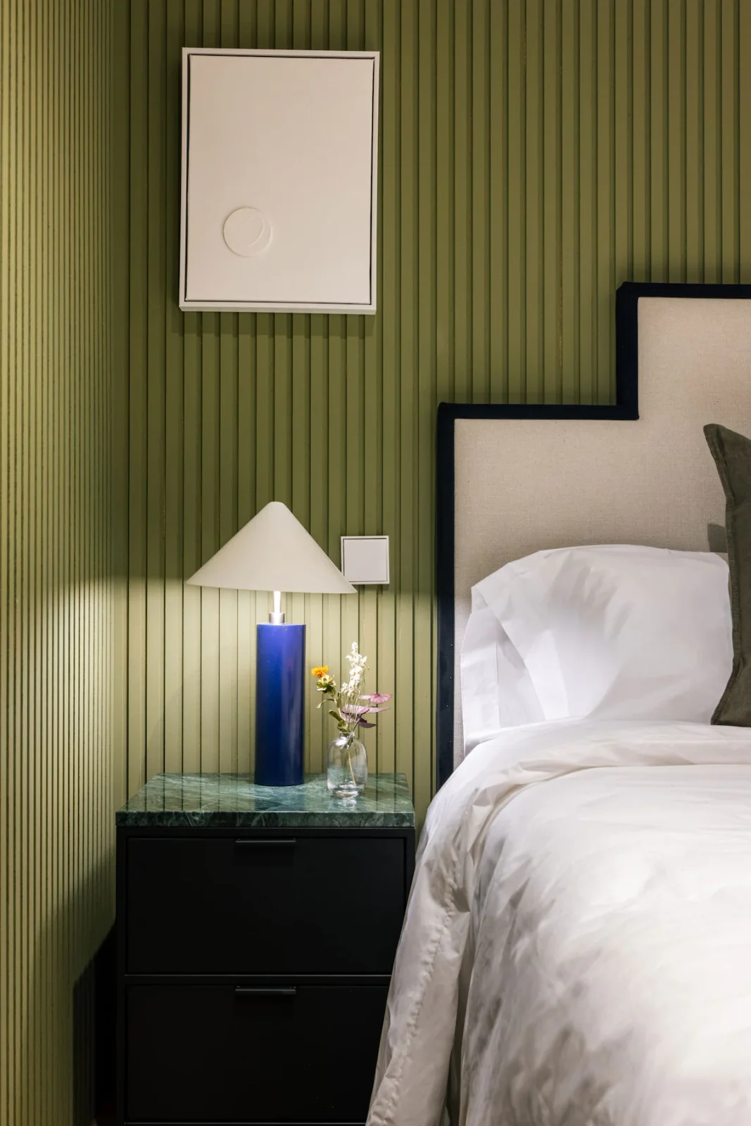 Olive reeded headboard wall with cobalt lamp and stepped headboard