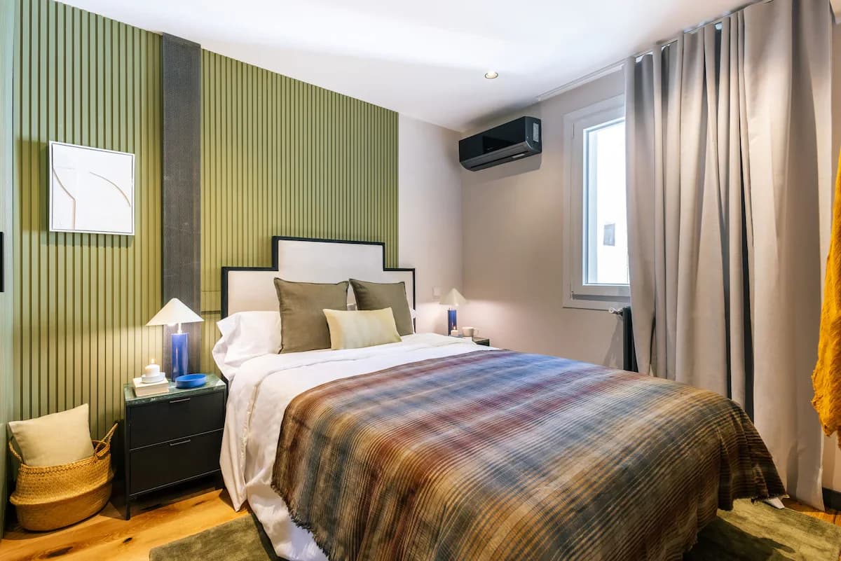 Olive panelled bedroom with framed bed and warm plaid throw