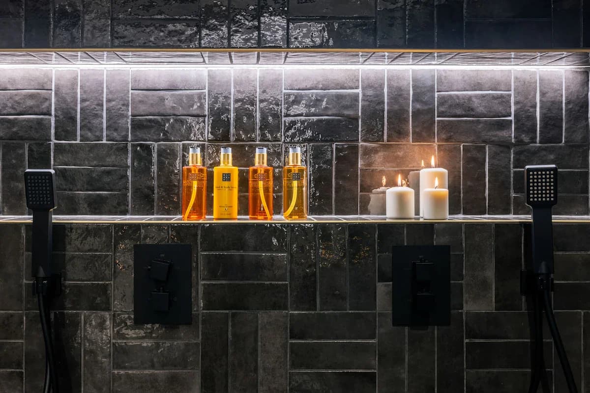 Shower niche styled with amber bottles and lit candles in shadow