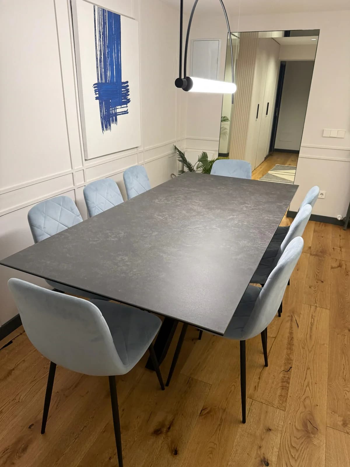 Stone dining table set for eight under sculptural arc light