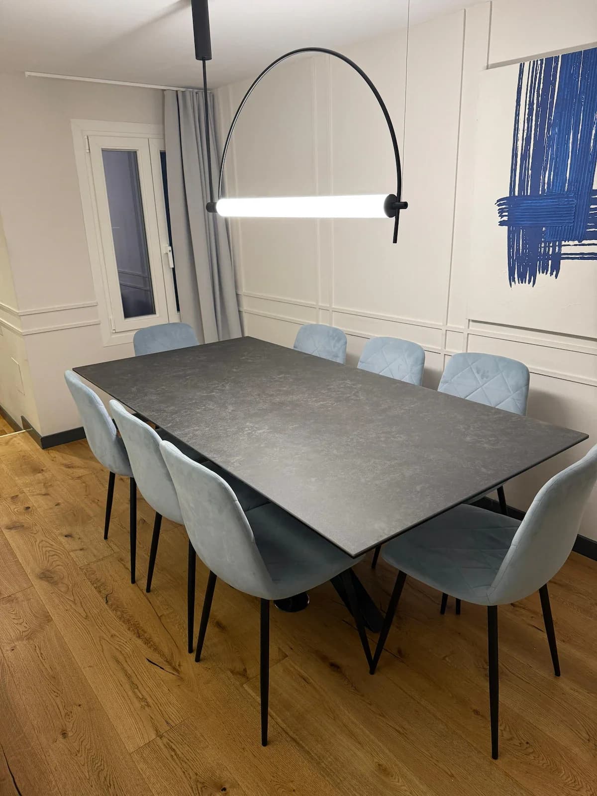 Long dining table with pale-blue chairs framed by panelled walls