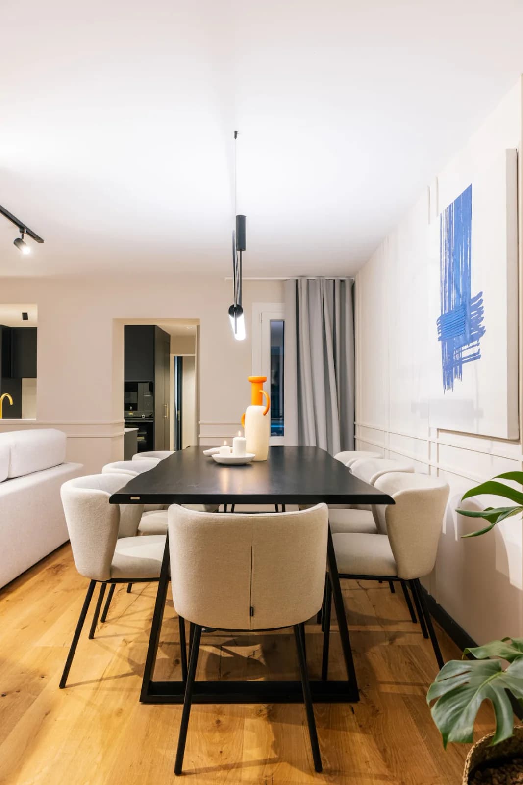 Dining and living open-plan with bouclé chairs and modern blue art
