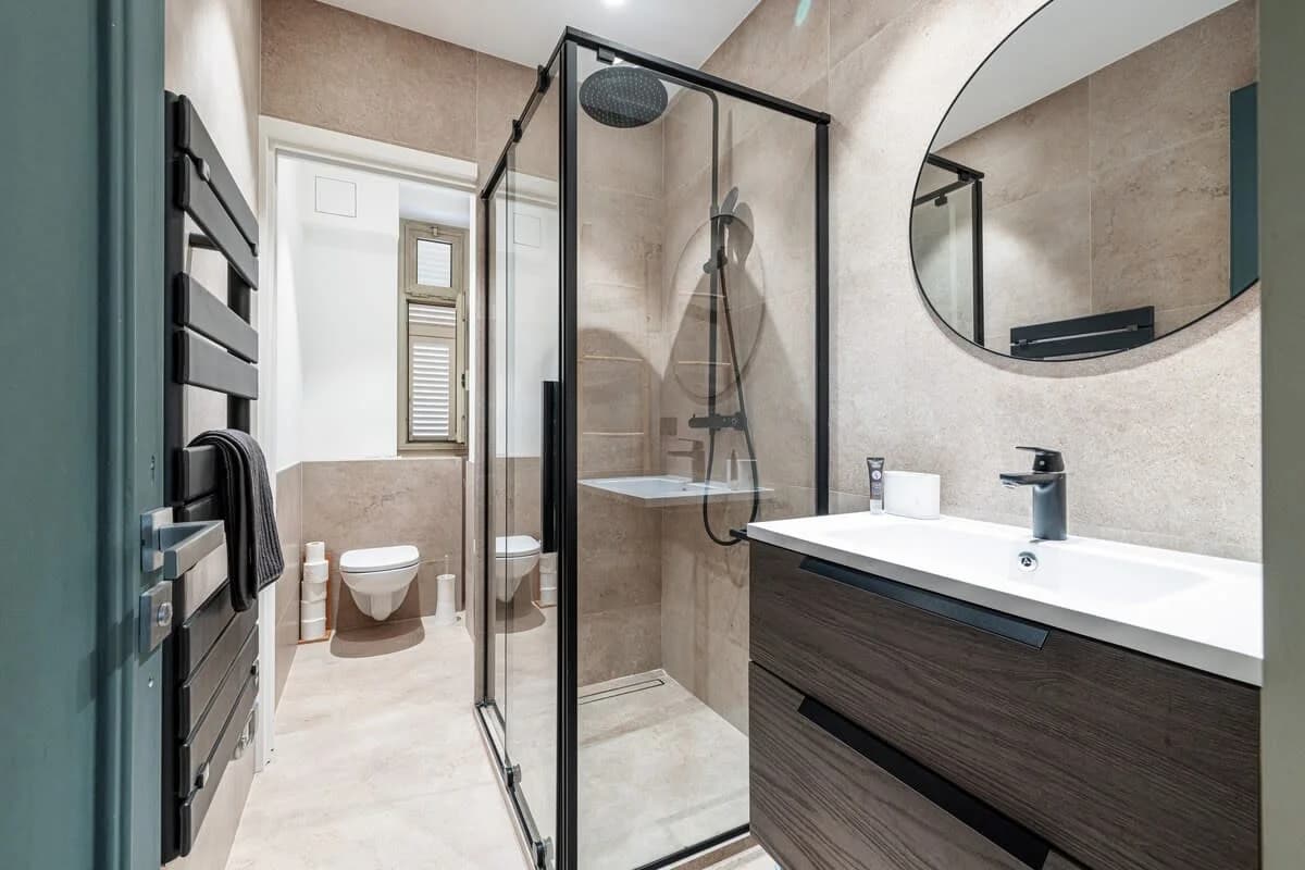 Black accents bathroom with heated towel rail and full-height shower glass