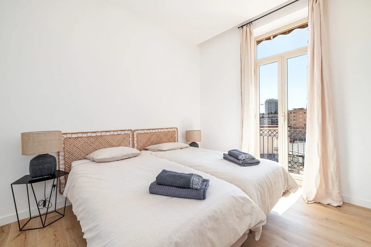 Serene main bedroom with rattan headboard and balcony doors open to city