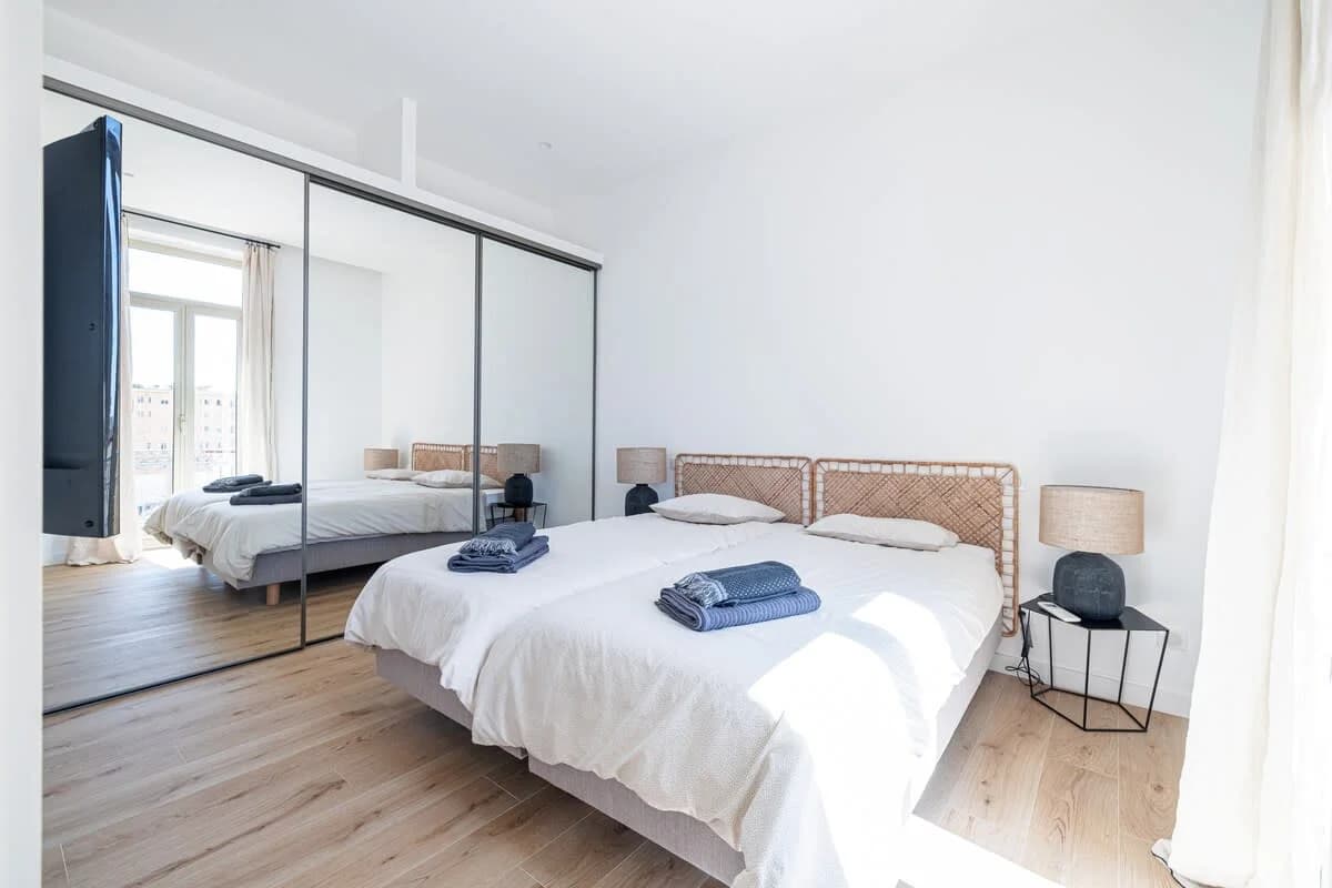 Twin bedroom with rattan headboards, mirrored wardrobe doubling the light