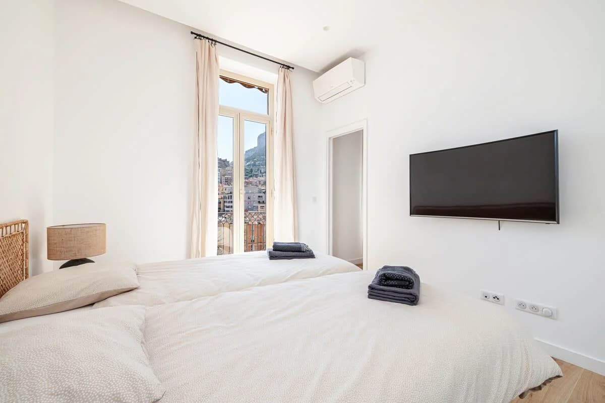 Calm second bedroom framing the rock face through tall French doors