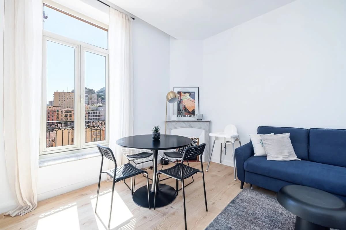 Sun-drenched dining nook with round black table beside an oversized window