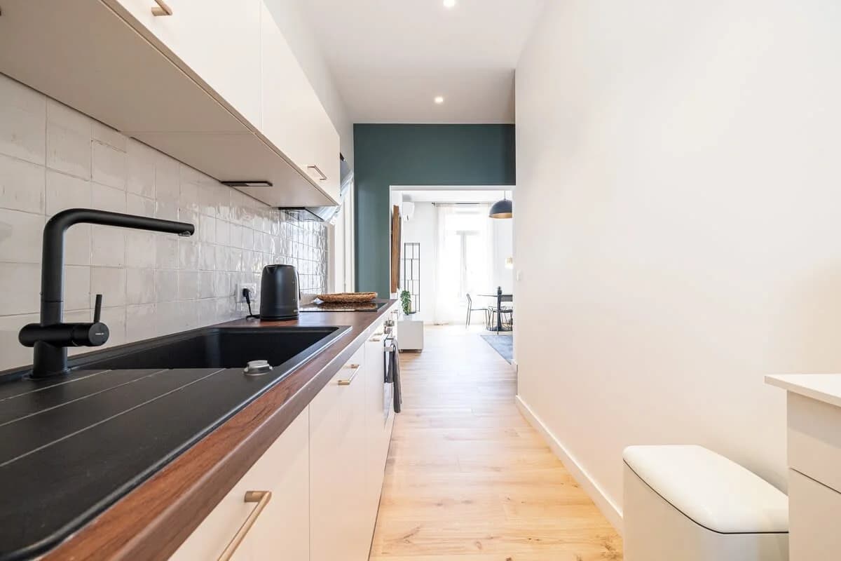 Kitchen corridor with matte black tap leading to teal-accented hallway