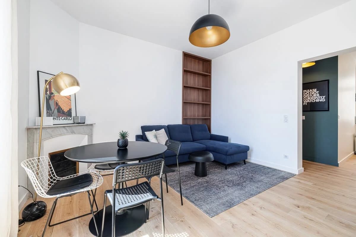 Living area with brass floor lamp, marble mantel and dining nook