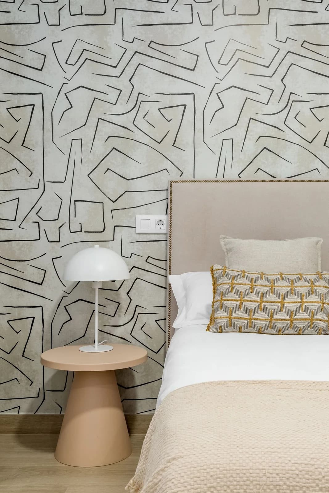 Headboard against hand-drawn maze wallpaper with mushroom lamp on terracotta plinth