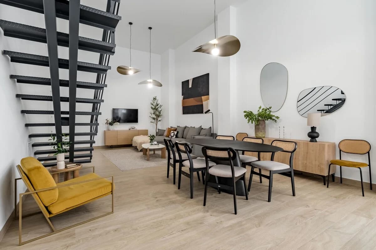 Wide loft view spanning living, dining and kitchen under double-height ceilings