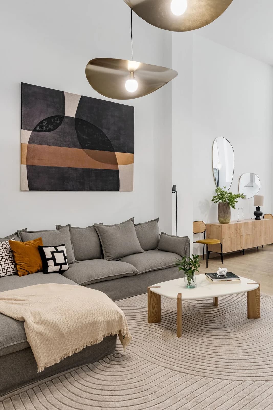 Linen sectional under brass petal pendants with bold abstract canvas