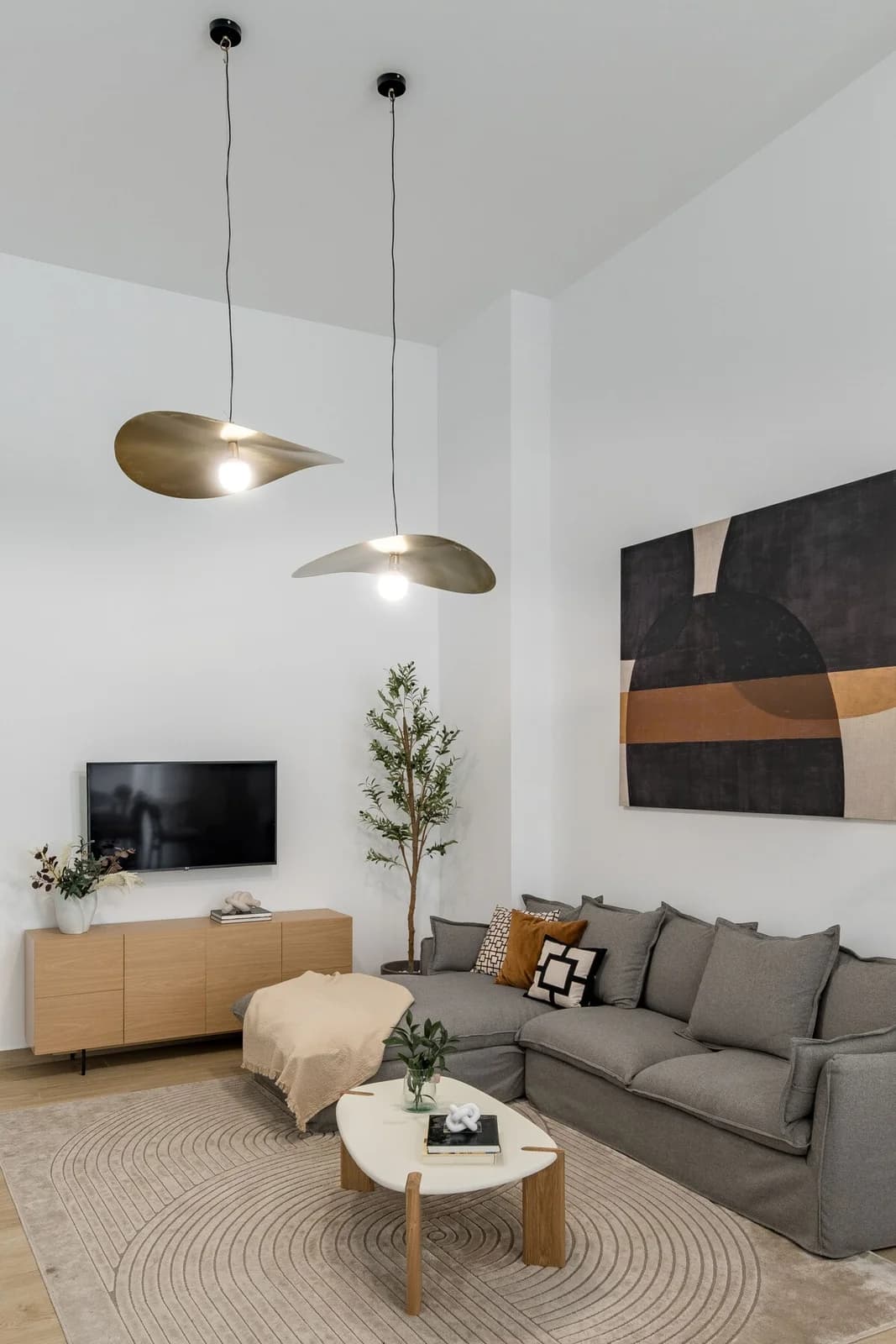 Living lounge with olive tree, gallery wall and double-pendant sculptural lighting