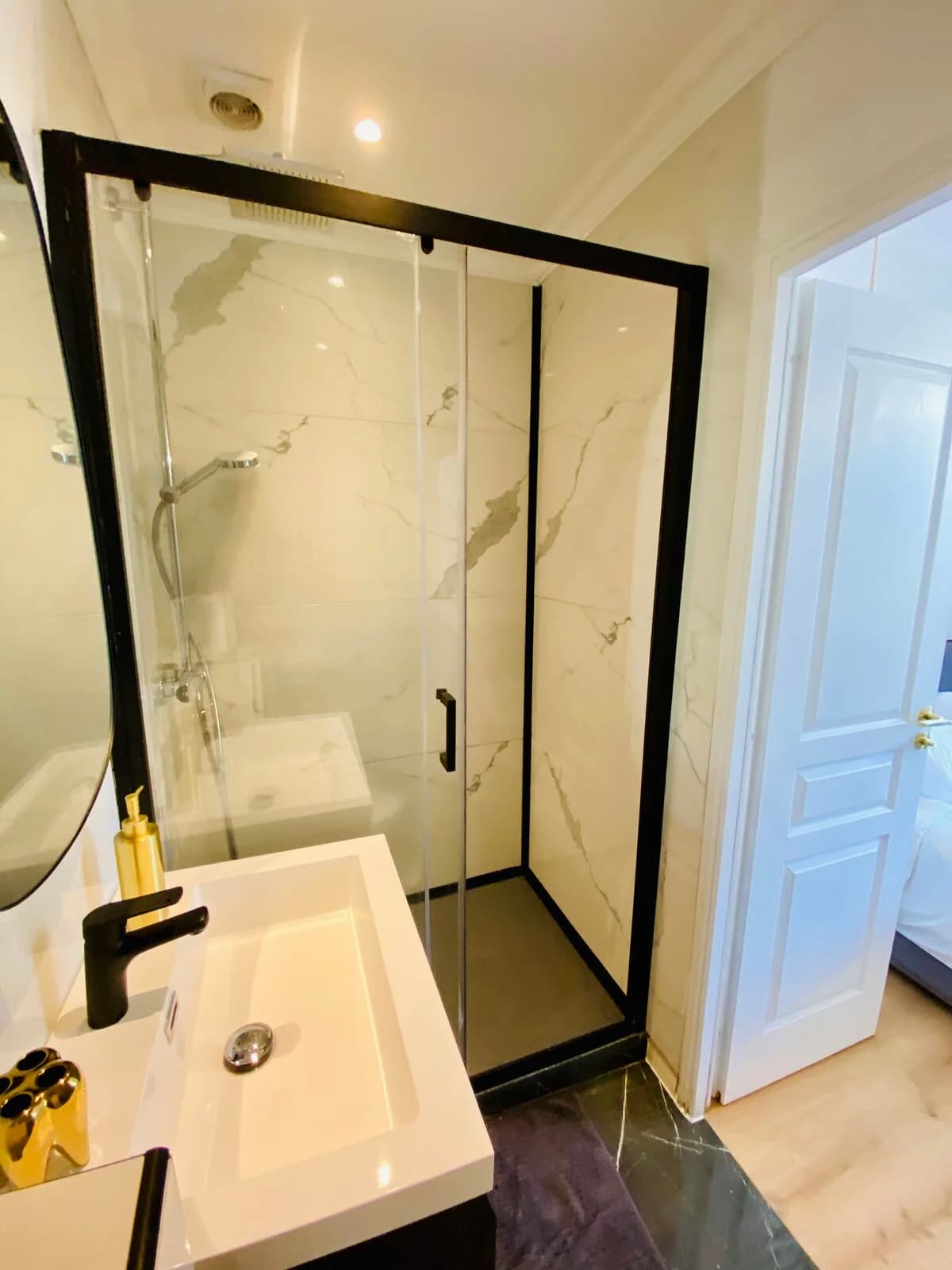 Marble walk-in shower with black framing and view to bedroom door