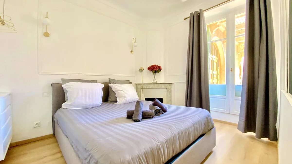 Main bedroom with marble fireplace and tall French doors flooding light