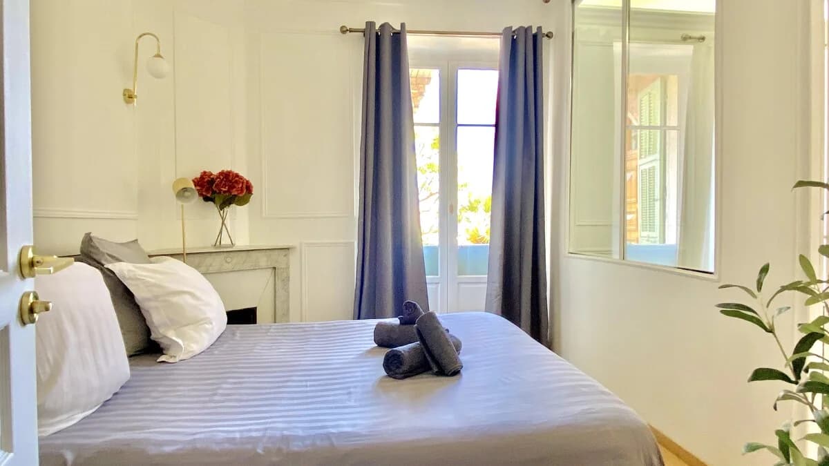 Calm bedroom view with brass sconce, hydrangeas on the marble mantel