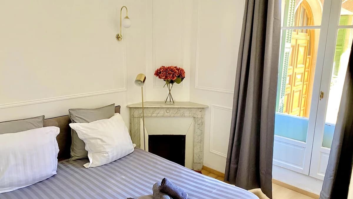 Marble fireplace with brass sconce and hydrangeas beside French doors