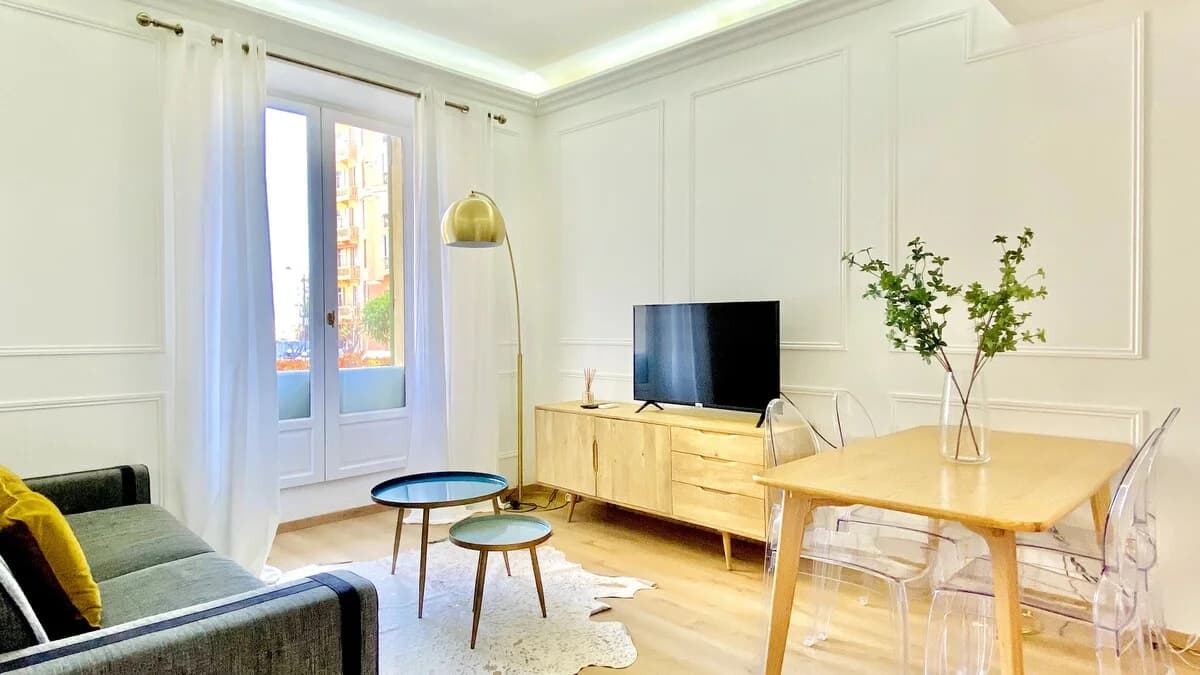 Bright living room with arc lamp, panelled walls and French doors to garden