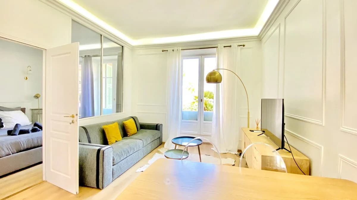 Living room view through to bedroom with brass arc lamp and panelled walls
