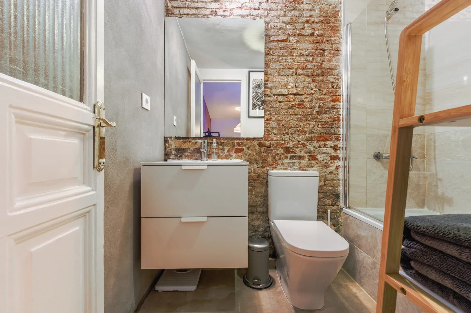 Bathroom view to brick wall, suspended vanity and tall mirror