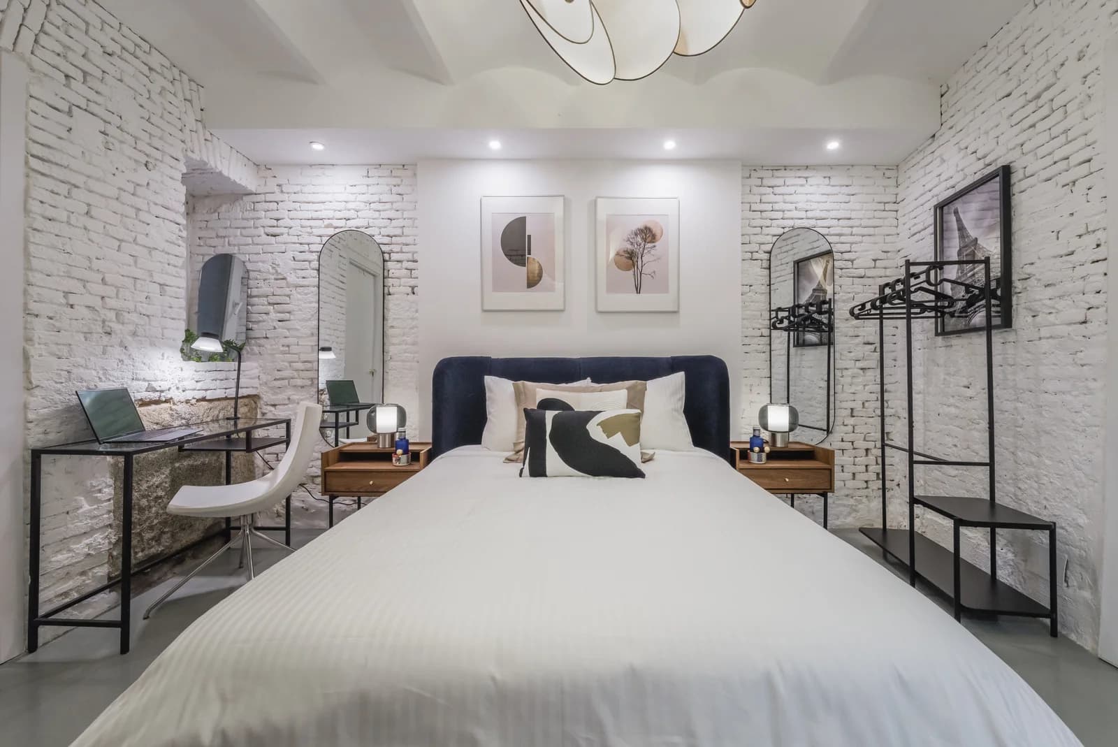 Whitewashed brick bedroom with arched mirrors and navy upholstered headboard