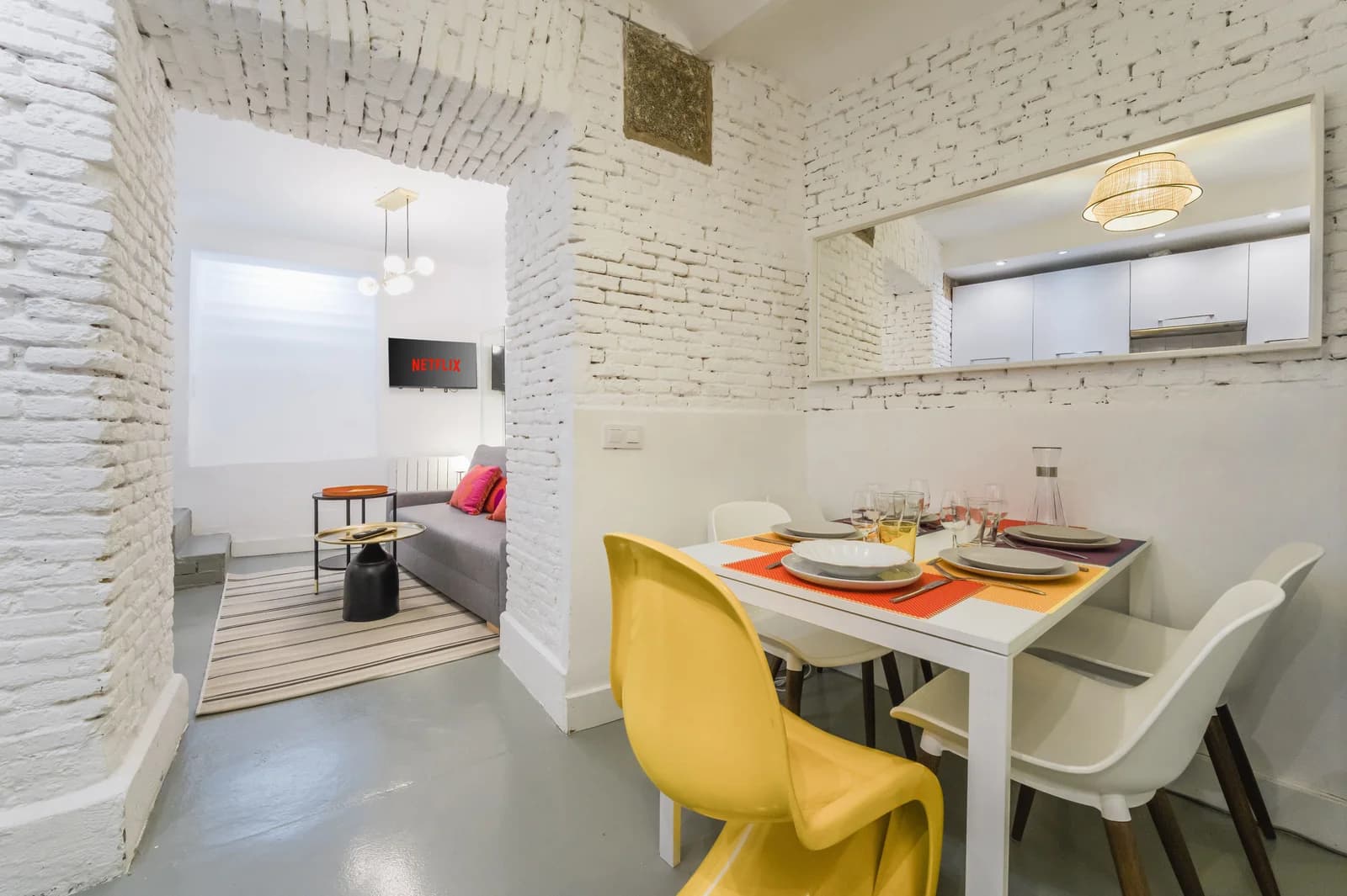 Dining table with yellow Panton chair against whitewashed brick arch
