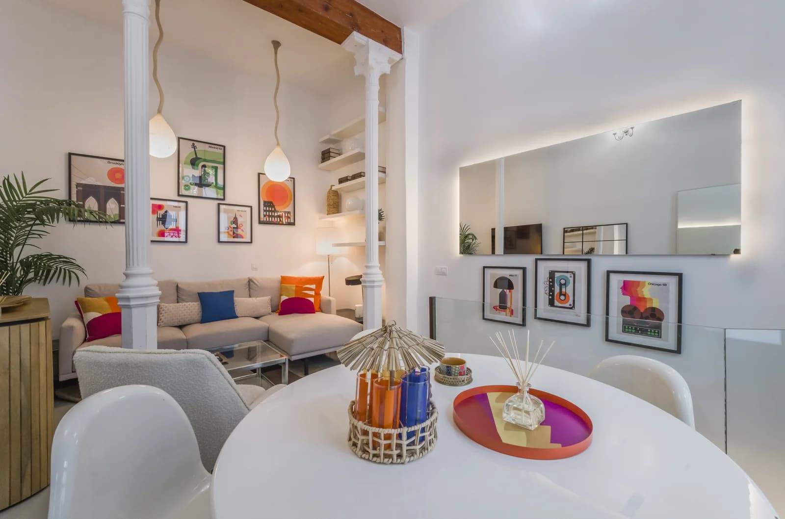 Open living-dining looking toward gallery wall with brass pendants